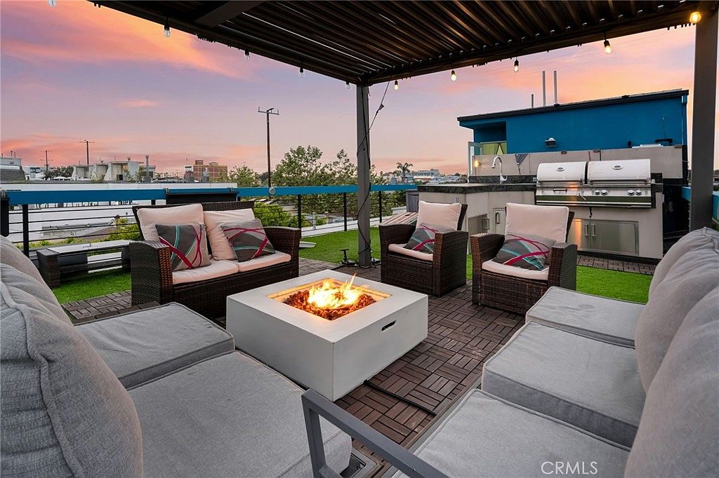 Rooftop deck at sunset with fire pit, outdoor kitchen, pergola, and sweeping Venice skyline